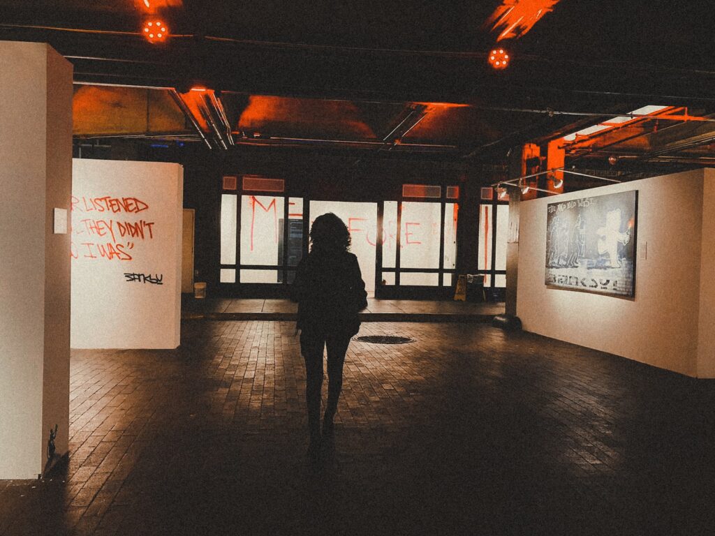 Silhouetted woman walking in Banksy exhibit at Underground Atlanta