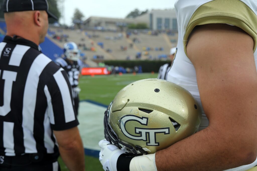 Football player and referee on the sidelines with a Georgia Tech football helmet
