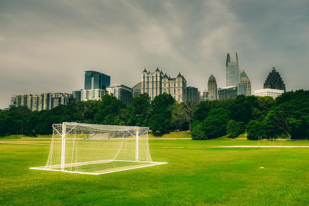 white soccer goal net on green grass field near city buildings during daytime in Piedmont Park in Atlanta