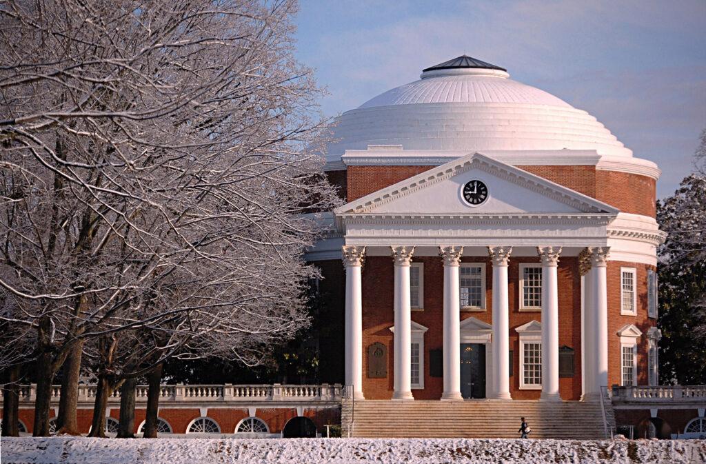 Rotunda of a red brick building with white columns and white dome surrounded by winter trees