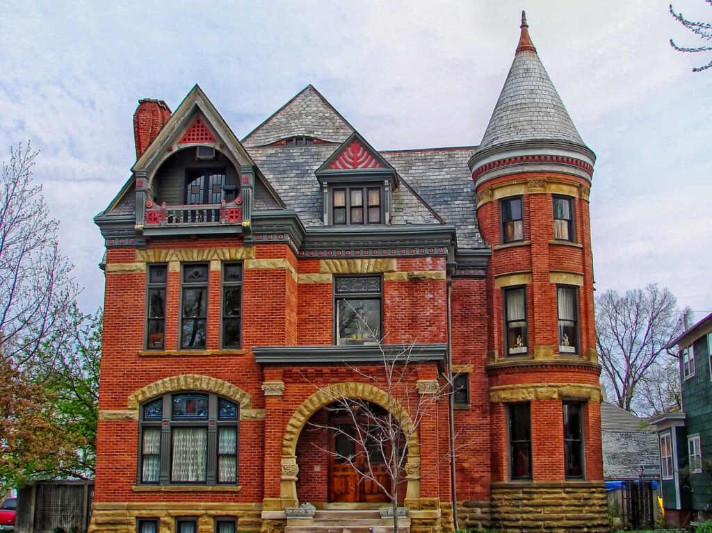 red brick two-story victorian home against a blue sky