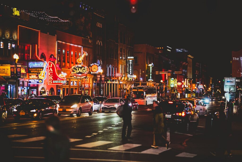 people walking on sidewalk during night time with neon signs on club fronts