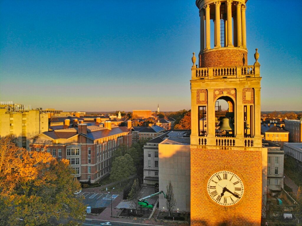 white and brown concrete clock tower overlooking a college campus