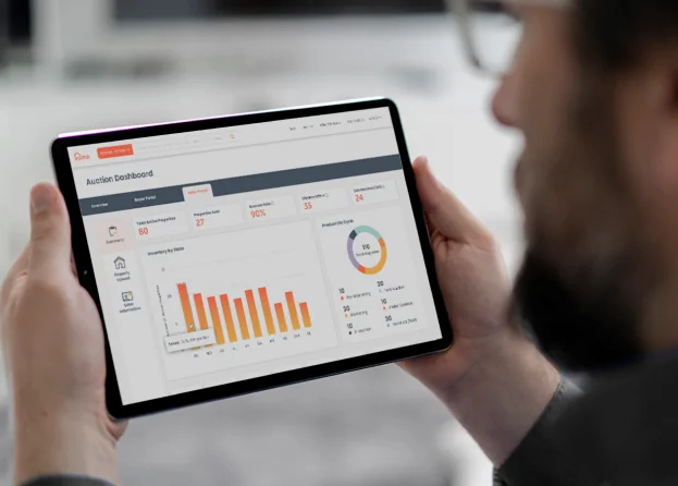 Man holding tablet showing Xome's auction dashboard